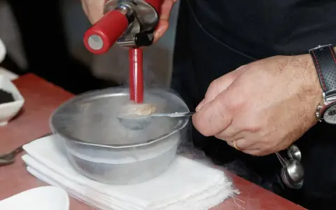 Chef usa sifón para crear texturas aireadas, ideal para recetas de espumas para sifón. Humo frío rodea el bol.