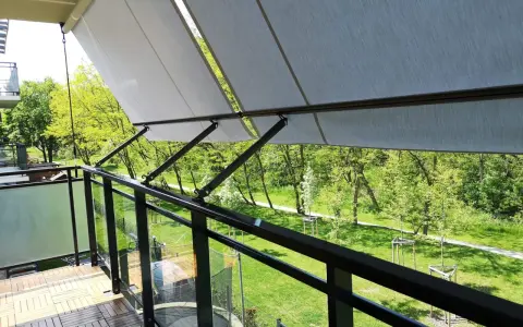 Nowy markiza to świetny sposób, jak osłonić balkon w bloku przed słońcem. Drewniana podłoga i szklane balustrady dodają uroku.
