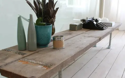 Une table basse rustique, idéale pour savoir que faire avec des vieilles planches de bois. Elle est décorée d'une machine à écrire, de vases et d'une bougie.