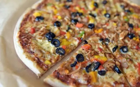 Pyszna pizza z oliwkami i kolorową papryką, jeden z wielu apetycznych rodzajów pizzy.