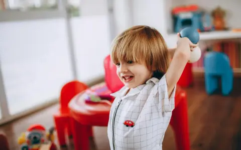 Chłopiec z piłeczkami w ręku, uśmiechnięty. Pokazuje, jak reagować na złość dziecka, gdy jest szczęśliwy.