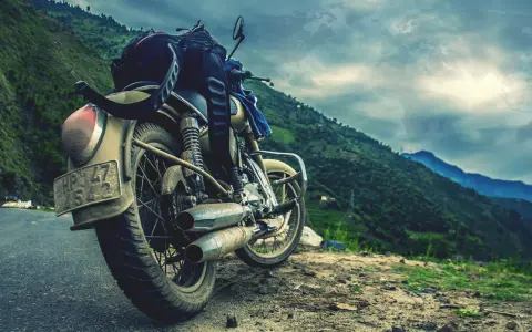 Motocykl gotowy na przygodę, z bagażem na siedzeniu, na tle gór i mapy świata. Marzy o podróży na Atlantic Road w Norwegii.