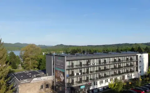 Widok na hotel Solina Resort & Spa z apartamentami i pokojami, otoczony zielenią, z jeziorem Solina w tle.