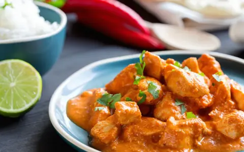 Un saporito spezzatino di pollo in salsa cremosa, guarnito con prezzemolo fresco, accompagnato da riso bianco, lime e peperoncino rosso.