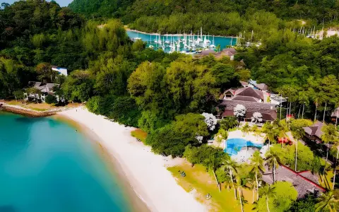 Widok z lotu ptaka na tropikalny kurort z plażą, basenem i mariną w Malezji.
