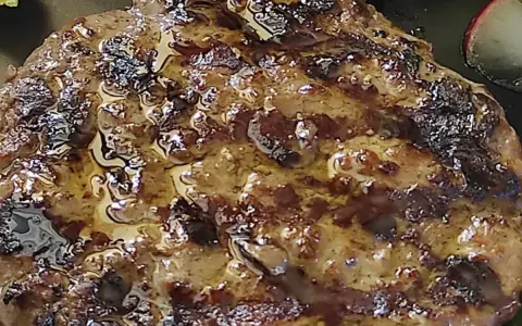 Hamburger in padella succulento, con crosticina dorata e succo che cola. Perfetto per un pasto veloce e gustoso.