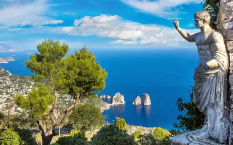 Statua antica guarda il mare blu intenso e i Faraglioni, icona dell'isola vicino Capri.