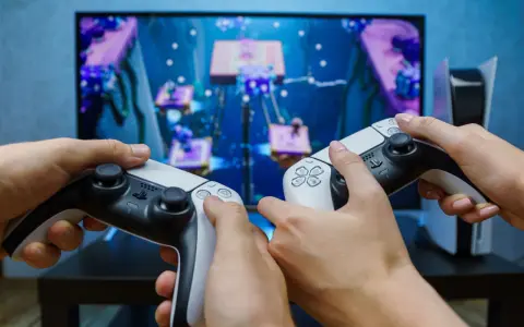 Dwie osoby grają w grę na konsoli PlayStation 5, trzymając kontrolery DualSense.