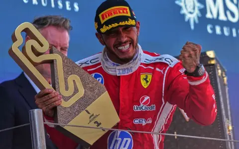Hamilton im Ferrari-Outfit jubelt mit Pokal.