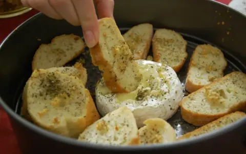 Ciepły, rozpływający się camembert z piekarnika, idealny do maczania w nim chrupiących grzanek z ziołami.
