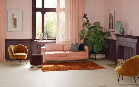 Przytulny salon z sofą w kolorze pudrowy róż, aksamitnym fotelem i dywanem w odcieniu miedzi.