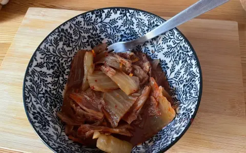 Miseczka z domowym kimchi, widelcem, na drewnianej desce.
