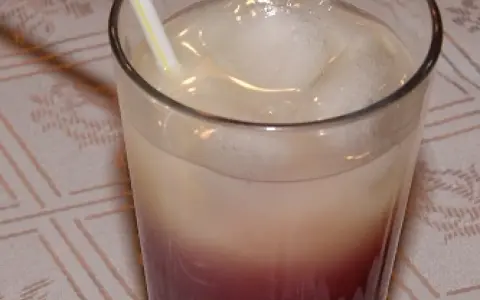 Szklanka z drinkiem z lodem i słomką, z widocznym podziałem na warstwy koloru.
