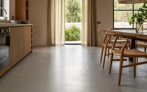Cocina moderna con muebles de madera y un elegante suelo microcemento que refleja la luz natural.