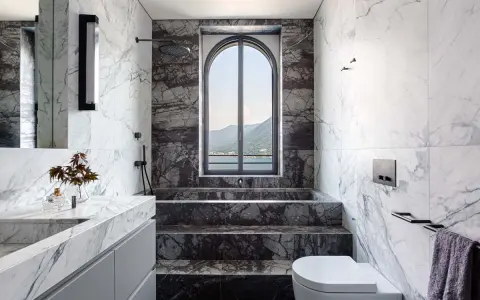 Bagno di lusso con vasca doccia in muratura, rivestimenti in marmo e vista panoramica.