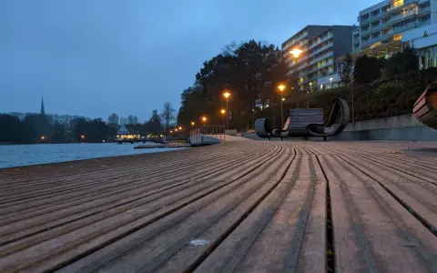 Holzdeck am See mit modernen Bänken und Beleuchtung. Ein schöner Ort für **Bad Segeberg Unternehmungen** am Abend.