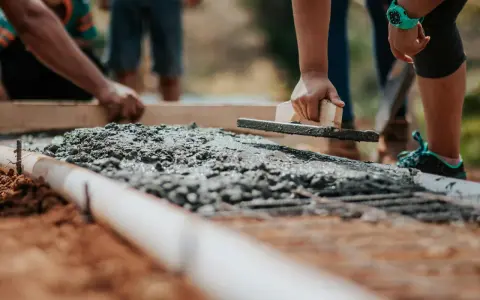 Pracownicy wygładzają świeży beton, dbając o jakość i cenę materiału.
