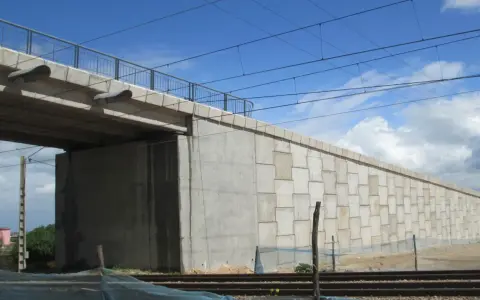 El estribo del puente de hormigón se alza imponente, sosteniendo la estructura sobre las vías del tren.