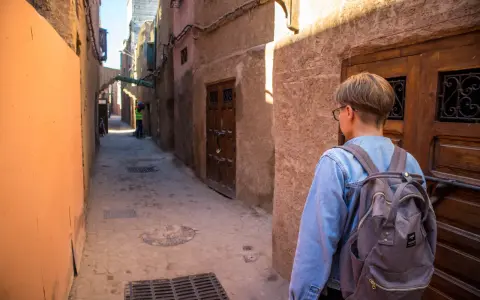 Młoda osoba z plecakiem idzie wąską uliczką w Marrakeszu. Czy w Marrakeszu jest bezpiecznie? Tak, zwiedzanie jest przyjemne.