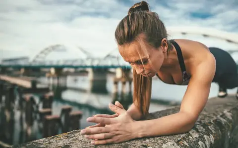Frau macht Liegestütze am Ufer, um ihren Körper fit zu halten. Training im Urlaub ist möglich!
