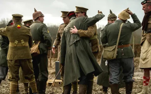 Des soldats en uniforme s'embrassent, une scène évoquant la trêve de Noël 1914.