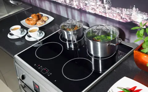 Plaque à induction moderne avec deux casseroles en marche, symbolisant la puissance et l'efficacité. Deux tasses de café et des viennoiseries sont prêtes pour le petit-déjeuner.