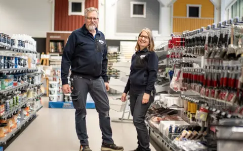 Två anställda står i en butik med färg och verktyg. De hjälper dig gärna att välja rätt färg för att måla fasad.
