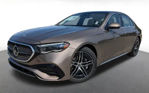 Elegancki brązowy Mercedes-Benz E450 sedan z czarnymi felgami stoi na szarym podłożu.