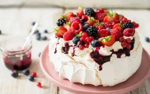 Beza pavlova która zawsze wychodzi, udekorowana bitą śmietaną i mnóstwem świeżych owoców leśnych.