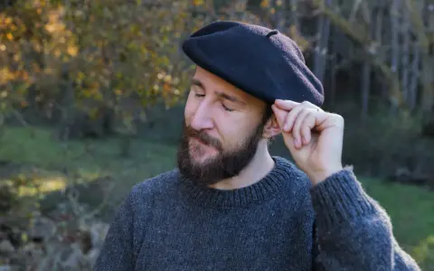 Hombre con barba ajustando su boina de lana, ideal para aprender como hacer una boina de lana.
