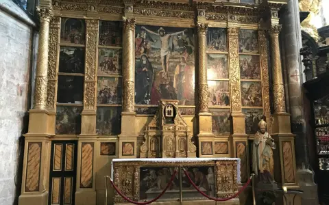 The ornate altar of the Basilica of Mary Magdalene features a central crucifixion scene surrounded by smaller narrative paintings, all set within a gilded structure.