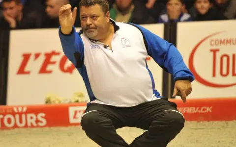 Un joueur de pétanque français connu, en pleine action, lance sa boule.