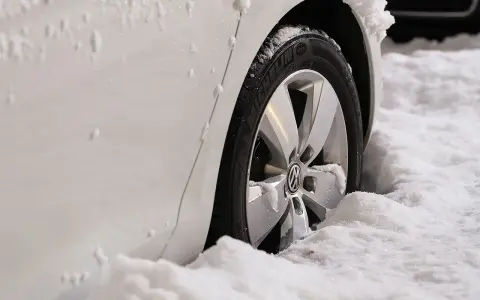 Białe auto w śniegu, widoczna felga z logo VW. Zastanawiasz się, jak zmierzyć rozstaw śrub?