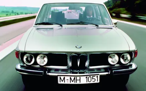 Srebrne BMW E3 z lat 70. jedzie po drodze.