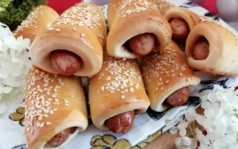 Złociste, pieczone mini hot dogi posypane sezamem, gotowe do podania. Idealne na przekąskę!