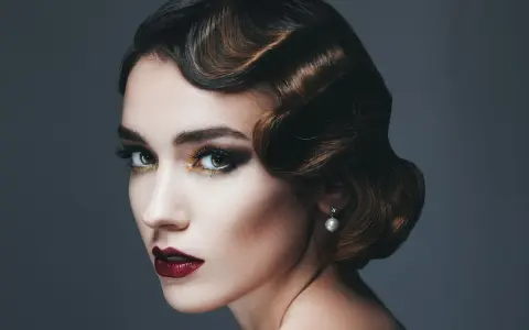 Glamouröse Frau mit einer eleganten 20er Jahre Frisur, dramatischem Make-up und einem Perlenohrring.
