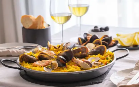 En härlig paella med skaldjur och ris, perfekt att avnjuta med ett glas vitt vin till paella. Serveras med citronklyftor och oliver.