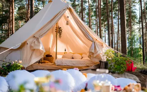 Przytulny namiot w lesie, idealny na glamping w Polsce. Wygodne łóżko, dekoracje i otoczenie natury tworzą magiczną atmosferę.
