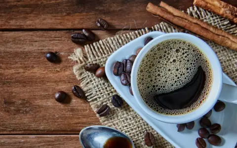 Heißer Kaffee mit Zimt, frisch zubereitet von einem Vollautomaten, duftet auf rustikalem Holz.