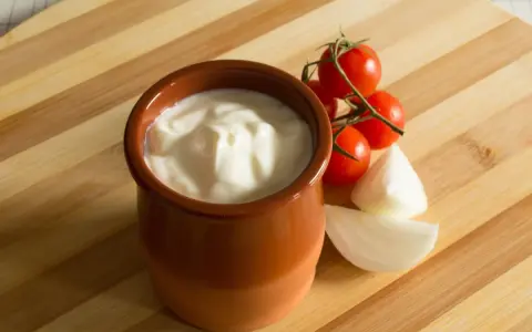 Gęsty jogurt w glinianym naczyniu, pomidorki koktajlowe i cebula. Jak zmniejszyć ostrość potrawy? Dodaj jogurtu!