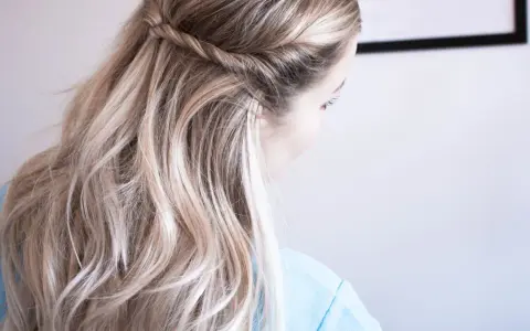 En kvinna med vackert, halvt uppsatt hår med en flätad detalj. Håret är blont och vågigt.