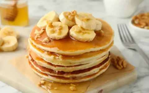 Pancakes leggeri con banane e noci, una deliziosa ricetta pancake light, guarniti con sciroppo d'acero e miele.