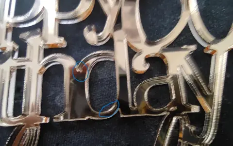 Close-up of a "Happy Birthday" acrylic mirror cake topper, showing the delicate edges and some minor imperfections from how to cut acrylic mirror.