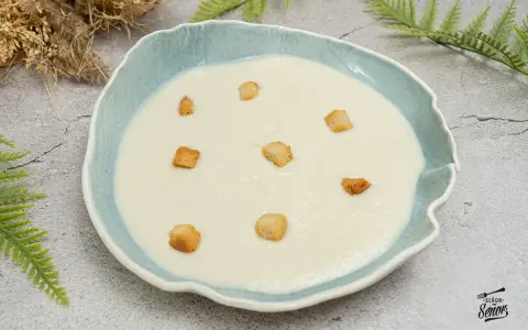 Crema de coliflor suave y cremosa, decorada con crujientes picatostes dorados en un cuenco azul.
