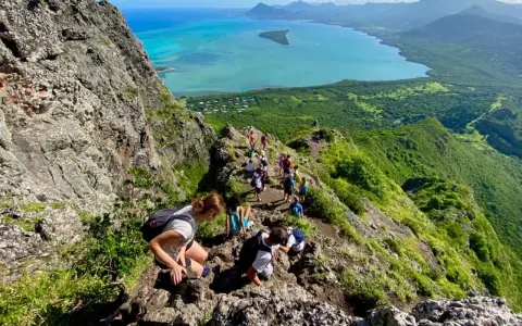 Grupa turystów wędruje po skalistym szlaku na Le Morne Mauritius, podziwiając zapierający dech w piersiach widok na turkusową lagunę i zielone wzgórza.