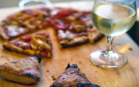 En saftig pizza med ett glas vitt vin till. Perfekt för en mysig kväll.