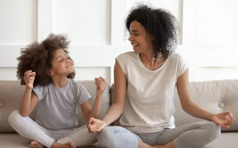 Madre e hija meditando juntas, fomentando sus habilidades de afrontamiento. Ambas sonríen y parecen relajadas.