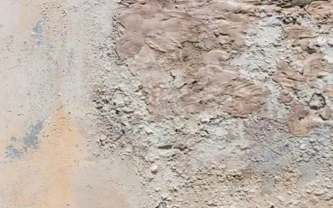 Texture d'un vieux mur dégradé, révélant des traces de salpêtre et des couches de peinture écaillée.
