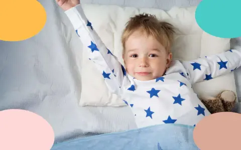 Niño de 3 años, con pijama de estrellas, estirándose en la cama.