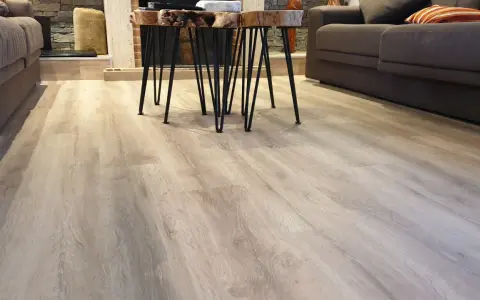 El suelo laminado o parquet de madera clara se extiende por la sala, reflejando la luz.